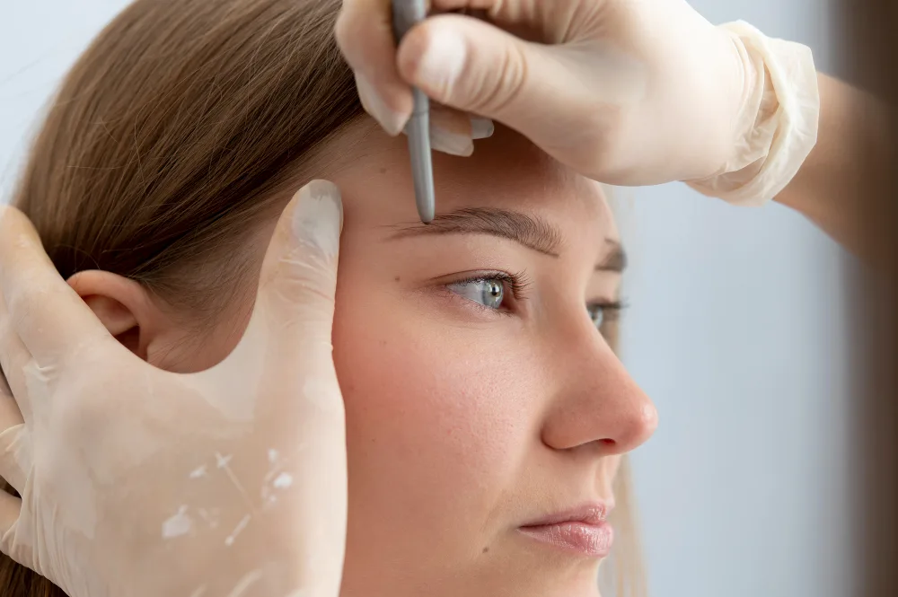 Specialist marking a woman's eyebrow shape before an eyebrow transplant