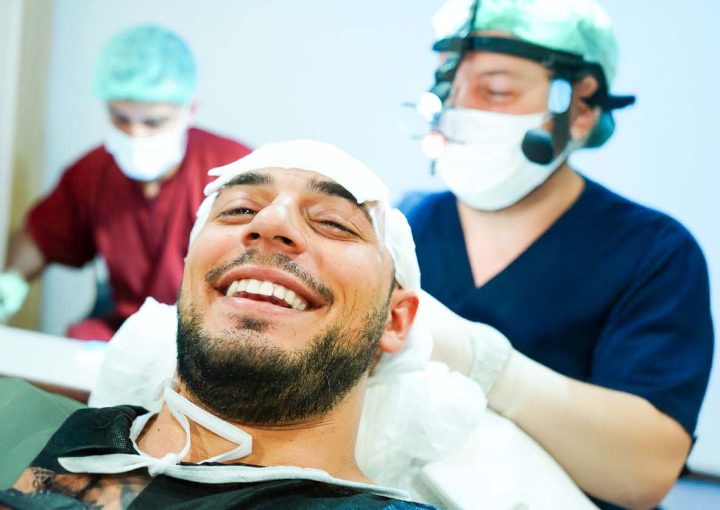 The Advantages and Disadvantages of Hair Transplants: Full Guide 10 A male patient smiling comfortably at the camera during a painless hair transplant procedure in Turkey