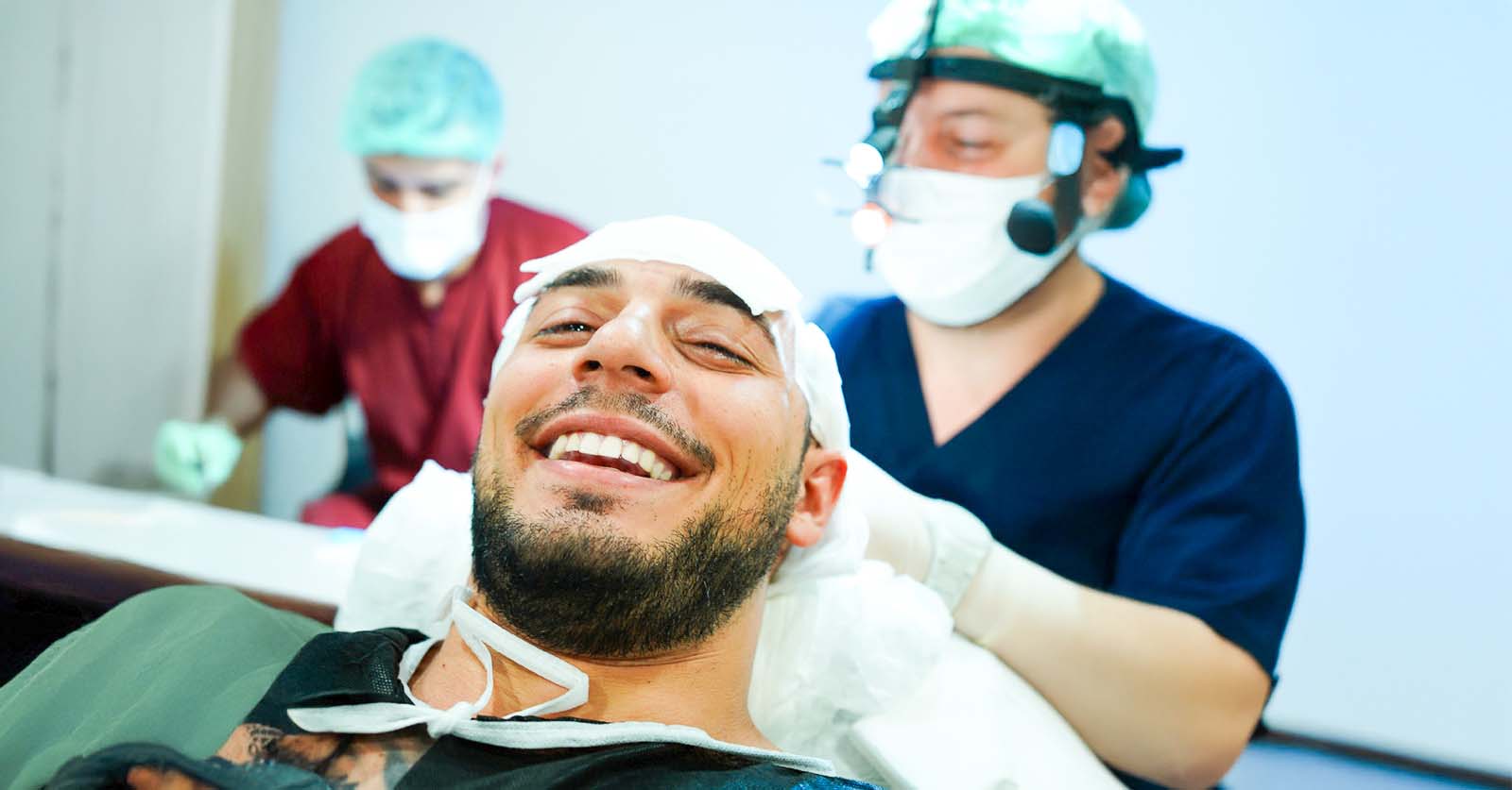 A male patient smiling comfortably at the camera during a painless hair transplant procedure in Turkey