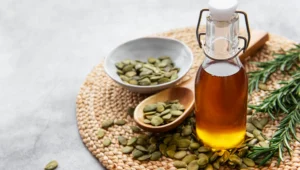 Bottle of pumpkin seed oil with pumpkin seeds and rosemary, a natural oil used for hair growth