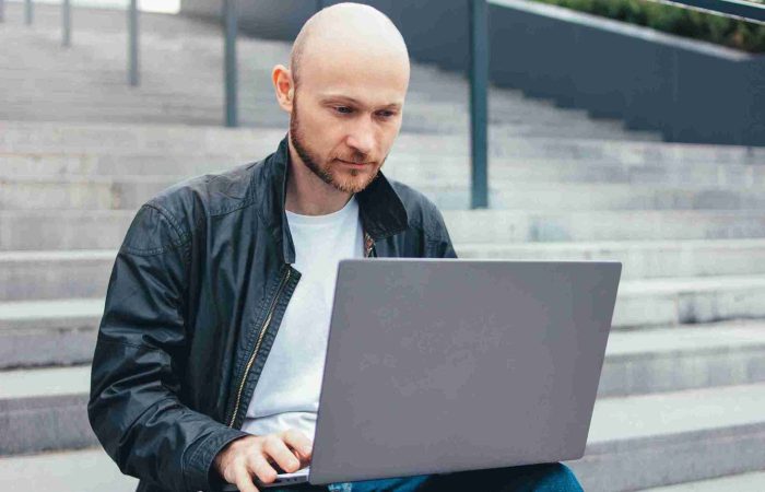 Haartransplantation Forum – Betroffene unter sich 7 Mann stöbert durch Haartransplantation Foren am Laptop.