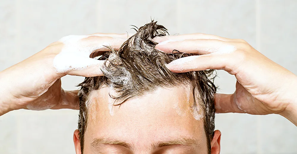 Man gently shampooing his hair and scalp, showing washing technique after a hair transplant
