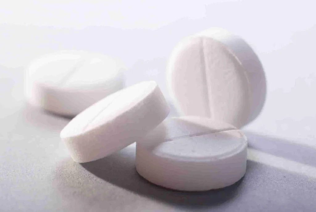 Weiße Aspirin Tabletten als Symbol für die Anwendung von Aspirin für die Haare gegen Schuppen, Verfärbungen und Haarausfall.