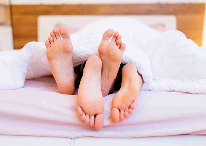 Sex nach Haartransplantation: Wann ist es wieder sicher? 3 Symbolisches Bild für Sex nach Haartransplantation – zwei Personen liegen im Bett unter einer Decke, ihre Füße ragen hervor.