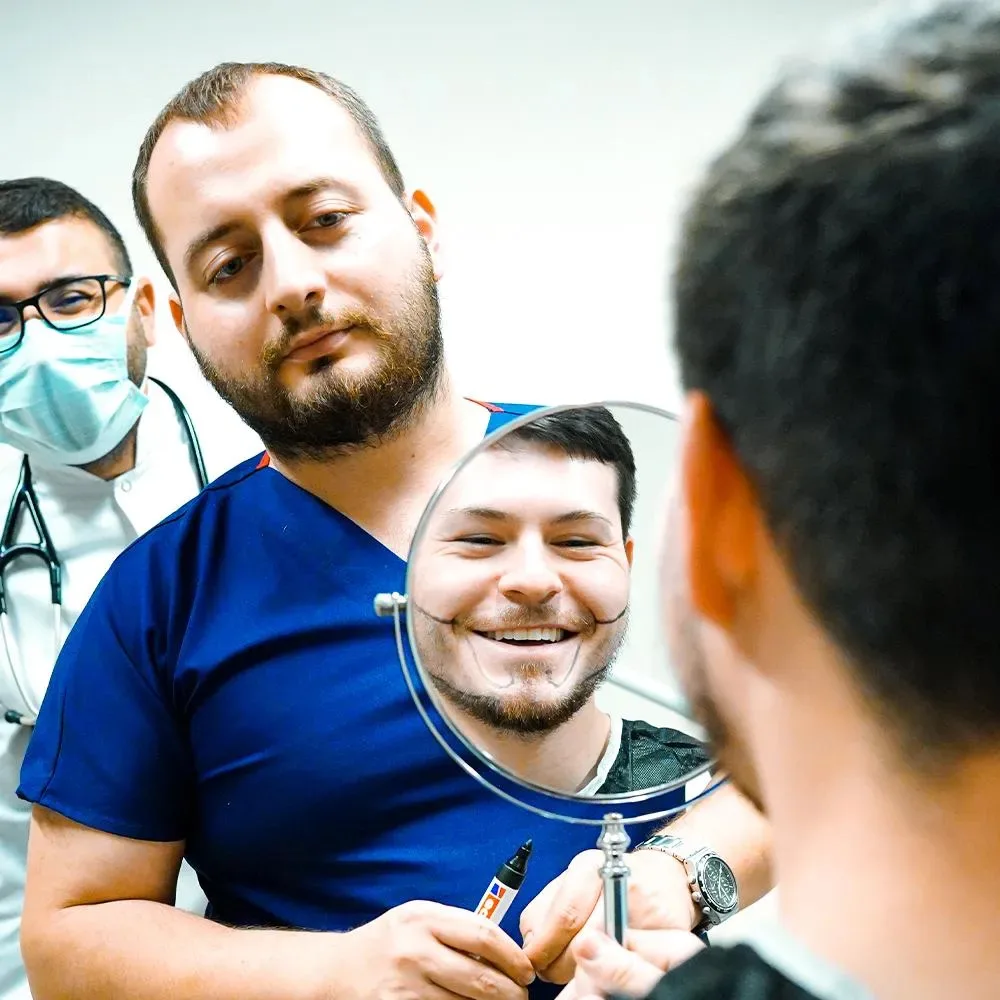 Paziente barbuto sorridente che si guarda in uno specchio a mano con il team medico