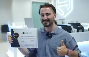 Patient souriant aux cheveux longs tenant son certificat Hermest