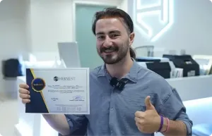 Patient aux cheveux longs souriant tenant son certificat Hermest après une greffe de cheveux