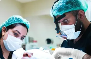 Deux membres de l'équipe masqués en charlotte travaillant sur un patient pendant une greffe de cheveux