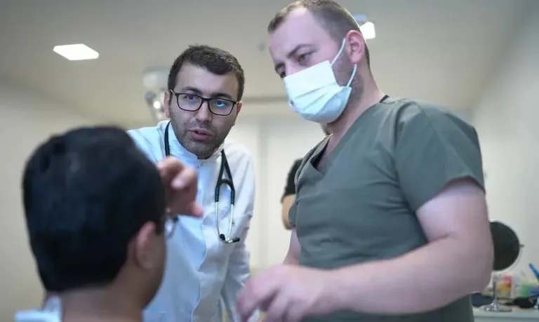 Médecin en blouse blanche et membre de l'équipe examinant les cheveux d'un jeune patient