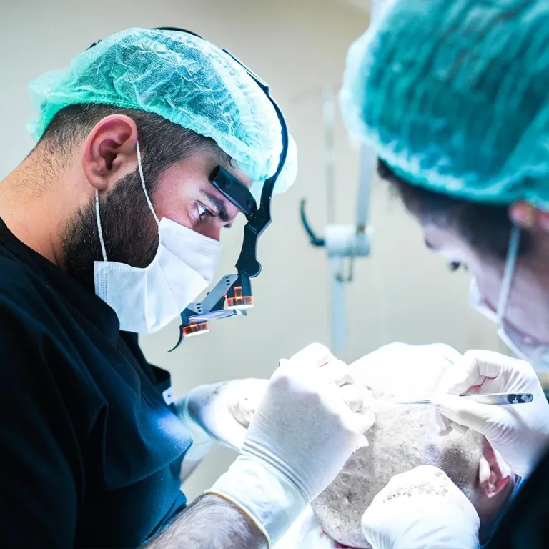 Chirurgien avec loupes et assistante travaillant sur le cuir chevelu d'un patient