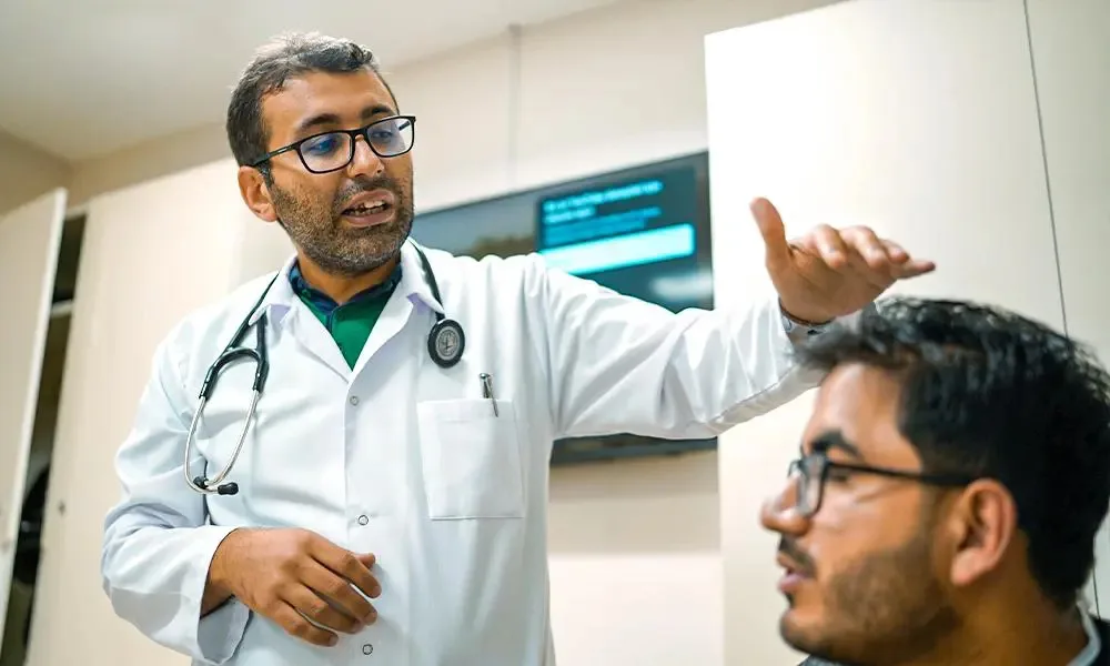 Médecin en blouse blanche expliquant le déroulement d'une greffe de cheveux à un patient