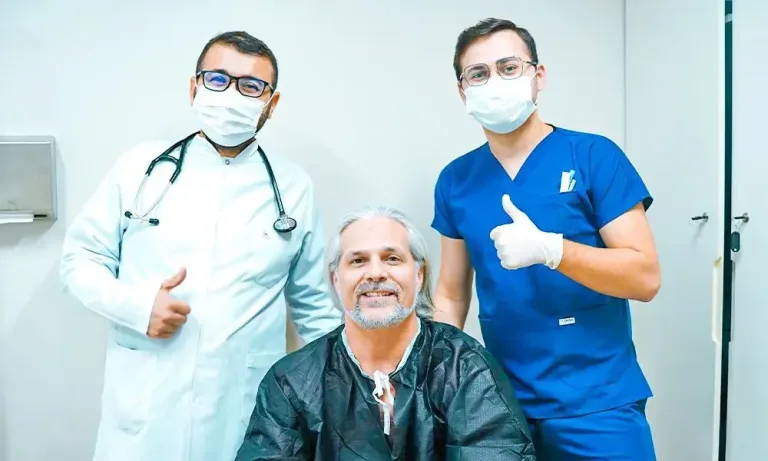 Paziente con i capelli grigi tra due membri del team medico con il pollice in su