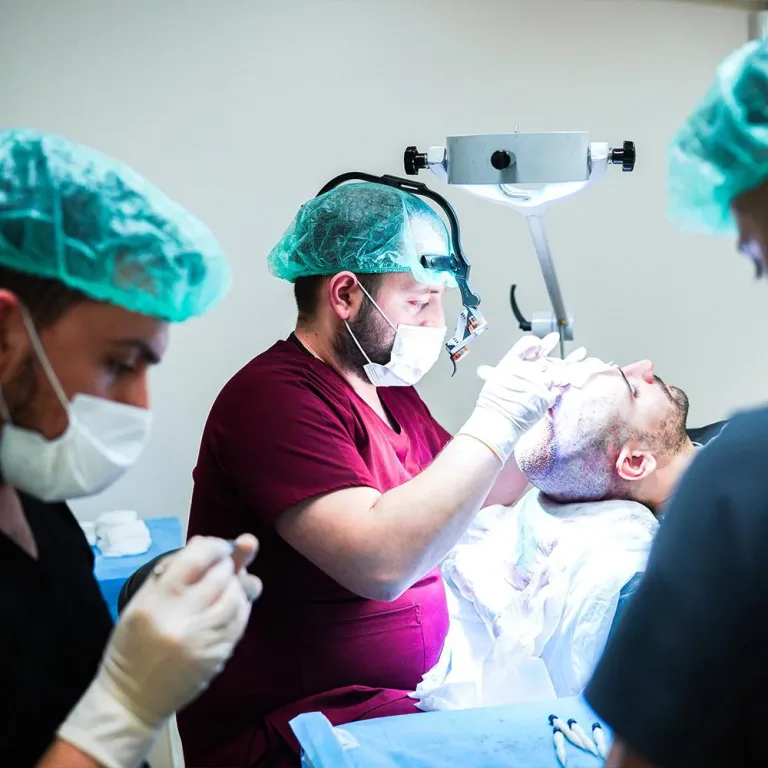 Team del trapianto di capelli al lavoro intorno a un paziente in sala operatoria